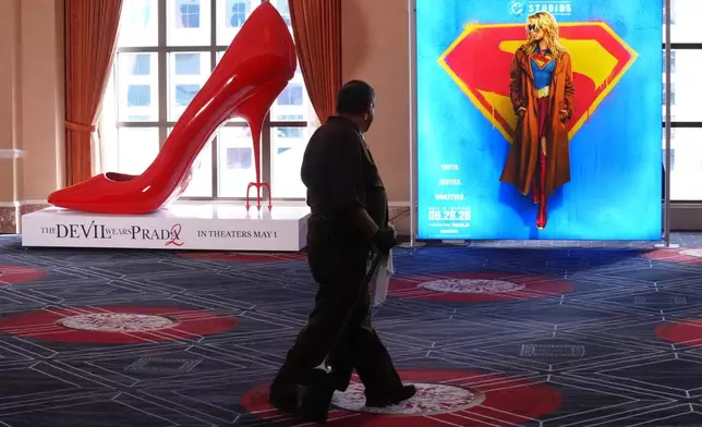 A maintenance worker walks past advertisements for the upcoming films "The Devil Wears Prada," left, and "Supergirl" during the opening day of CinemaCon 2026, the official convention of Cinema United, on Monday, April 13, 2026, at Caesars Palace in Las Vegas. (AP Photo/Chris Pizzello)