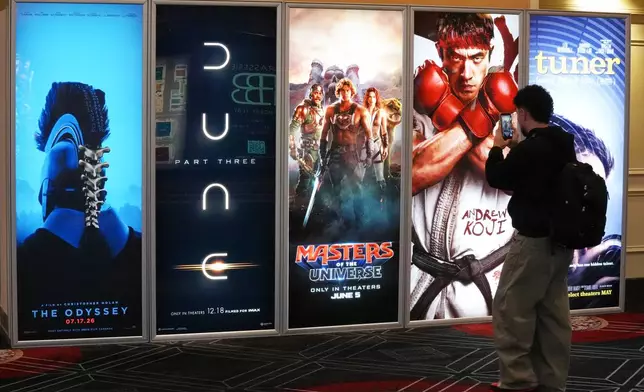 A CinemaCon attendee takes a picture of advertisements for upcoming films during the opening day of CinemaCon 2026, the official convention of Cinema United, on Monday, April 13, 2026, at Caesars Palace in Las Vegas. (AP Photo/Chris Pizzello)