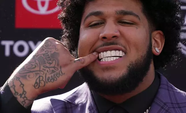 Alabama offensive lineman Kadyn Proctor shows off his dental jewelry while posing on the red carpet before the first round of the NFL football draft in Pittsburgh, Thursday, April 23, 2026. (AP Photo/Gene J. Puskar)