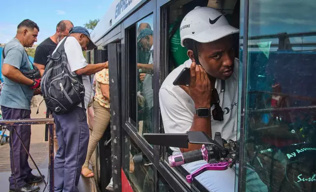 A man speaks on the phone while holding his electric bicycle in a public bus to cross the Bay Tunnel in Havana, Wednesday, April 8, 2026. (AP Photo/Ramon Espinosa)