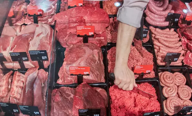 A woman works at the meat counter of a super market in Wehrheim near Frankfurt, Germany, Tuesday, March 31, 2026. (AP Photo/Michael Probst)