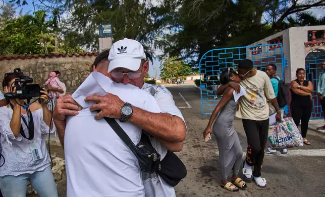 A pardoned prisoner, wearing cap, hugs a family member, as another kisses a woman after their release from La Lima penitentiary in Guanabo, Cuba, Friday, April 3, 2026. (AP Photo/Ramon Espinosa)