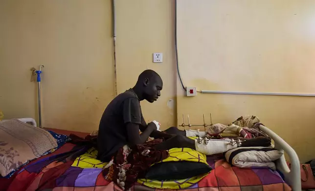Emadeldein Babiker, 17, who was injured in an explosion caused by unexploded ordnance, sits on a bed at Al Nao Hospital in Omdurman, on the outskirts of Khartoum, Saturday, April 18, 2026. (AP Photo/Bernat Armangue)