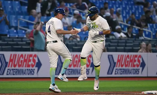 Tampa Bay Rays third base coach Brady Williams (4) and Jonathan Aranda, right, celebrate after Aranda's home run during the sixth inning of a baseball game against the Minnesota Twins, Friday, April 24, 2026, in St. Petersburg, Fla. (AP Photo/Jason Behnken)