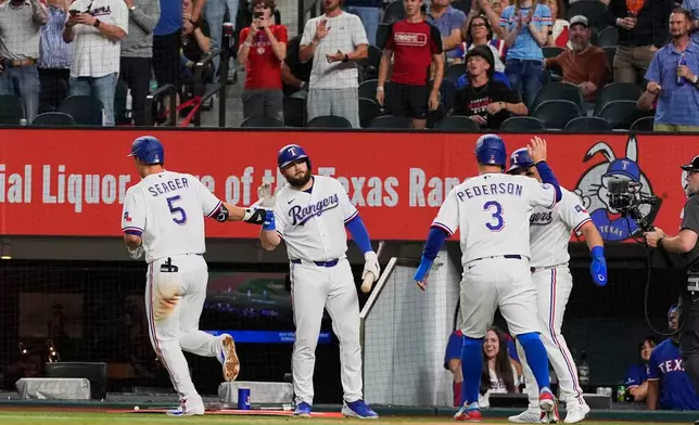 Texas Rangers' Corey Seager (5), Jake Burger, center rear, Joc Pederson (3) and Alejandro Osuna, right rear, celebrate Seager's three-run home run in the fourth inning of a baseball game against the Pittsburgh Pirates Thursday, April 23, 2026, in Arlington, Texas. (AP Photo/Tony Gutierrez)