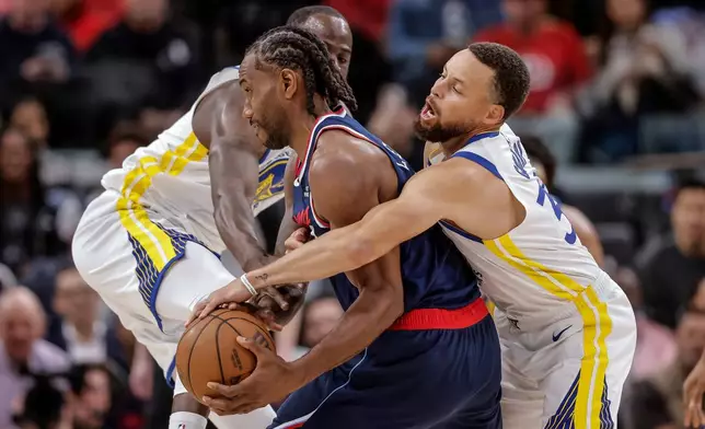 Golden State Warriors' Draymond Green, left, and Stephen Curry (30) defend against Los Angeles Clippers' Kawhi Leonard in the first half of an NBA play-in tournament basketball game in Inglewood, Calif., on Wednesday, April 15, 2026. (Carlos Avila Gonzalez/San Francisco Chronicle via AP)