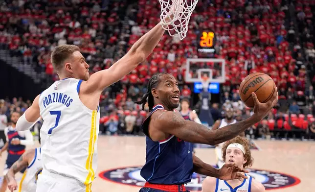 LA Clippers forward Kawhi Leonard, center, shoots as Golden State Warriors center Kristaps Porzingis defends during the first half of an NBA play-in tournament basketball game Wednesday, April 15, 2026, in Inglewood, Calif. (AP Photo/Mark J. Terrill)