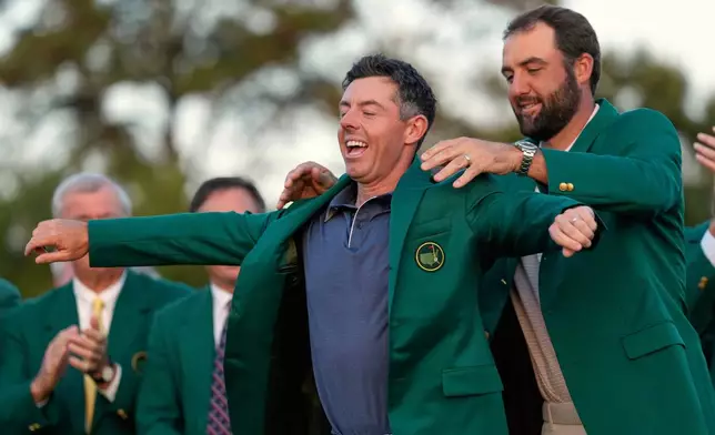FILE - Scottie Scheffler puts the green Jacket on winner, Rory McIlroy, of Northern Ireland, at the Masters golf tournament, April 13, 2025, in Augusta, Ga. (AP Photo/Ashley Landis, File)