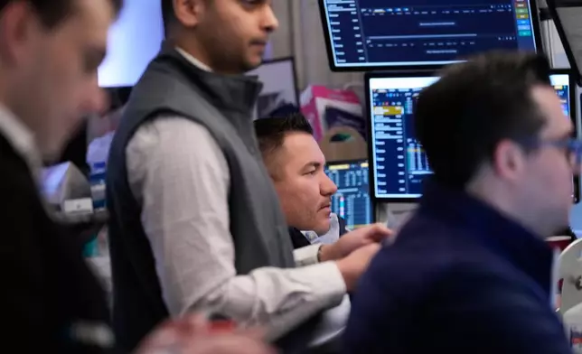 People work on the floor at the New York Stock Exchange in New York, Monday, April 13, 2026. (AP Photo/Seth Wenig)