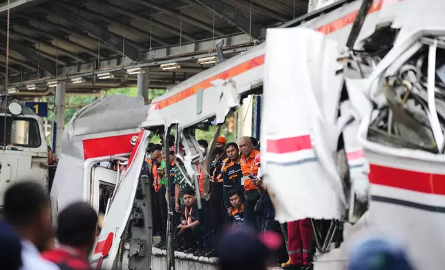 Workers and rescuers examine the wreckage following a train collision in Bekasi, Indonesia, Tuesday, April 28, 2026. (AP Photo/Tatan Syuflana)