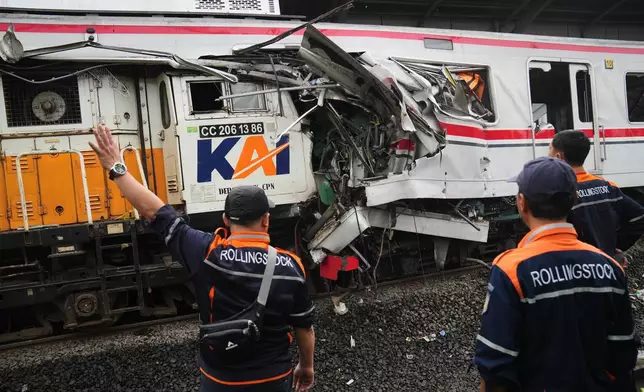 Workers examine the wreckages of trains after a collision in Bekasi, Indonesia, Tuesday, April 28, 2026. (AP Photo/Tatan Syuflana)