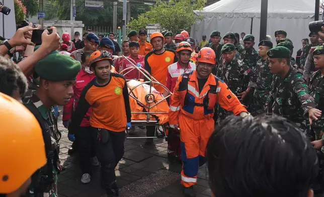 Rescuers carry the body of a victim of a train collision in Bekasi, Indonesia, Tuesday, April 28, 2026. (AP Photo/Tatan Syuflana)