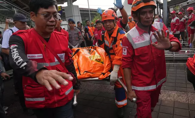 Rescuers carry the body of a victim of a train collision in Bekasi, Indonesia, Tuesday, April 28, 2026. (AP Photo/Tatan Syuflana)