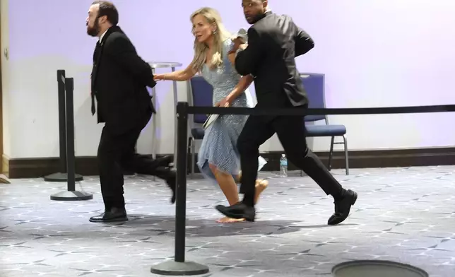 Guests are assisted and whisked away during the White House Correspondents Dinner, Saturday, April 25, 2026, in Washington. (AP Photo/Tom Brenner)