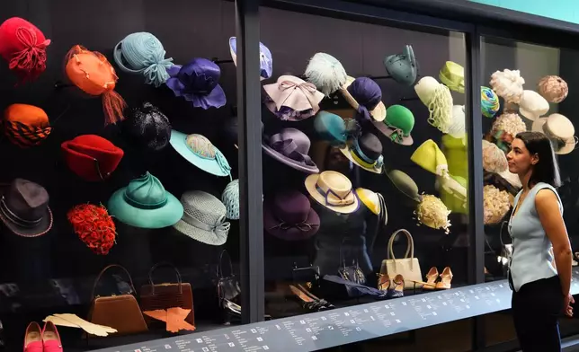 A member of the Royal Collection Trust staff looks towards hats, bags and shoes worn by Princess Elizabeth, on display at 'Queen Elizabeth II: Her Life in Style' exhibition, to mark the centenary of the late queen's birth, at The King's Gallery at Buckingham Palace in London, Thursday, April 9, 2026. (AP Photo/Kirsty Wigglesworth)