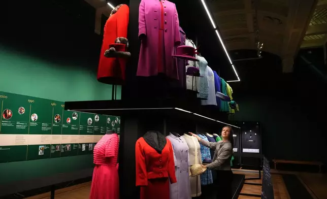 Cecilia Oliver, Textile Conservator at Royal Collection Trust adjusts day wear worn by Queen Elizabeth II, on display at 'Queen Elizabeth II: Her Life in Style' exhibition, to mark the centenary of the late queen's birth, at The King's Gallery at Buckingham Palace in London, Thursday, April 9, 2026. (AP Photo/Kirsty Wigglesworth)