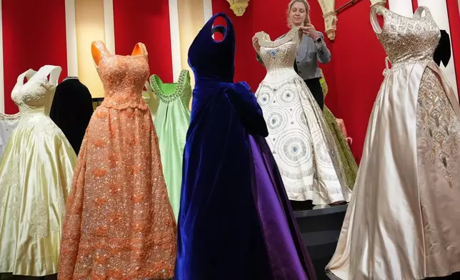 Cecilia Oliver, Textile Conservator at Royal Collection Trust adjusts a gown worn by Queen Elizabeth II, on display at 'Queen Elizabeth II: Her Life in Style' exhibition, to mark the centenary of the late queen's birth, at The King's Gallery at Buckingham Palace in London, Thursday, April 9, 2026. (AP Photo/Kirsty Wigglesworth)