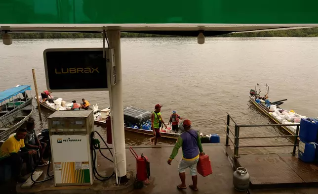 FILE - Boatmen operating Catraia, a traditional boat used on the Oiapoque River, prepare for the crossing with a load of gasoline canisters filled at a Petrobras gas station in a port in the city of Oiapoque, Amapa state, Brazil, March 10, 2026. (AP Photo/Eraldo Peres, File)