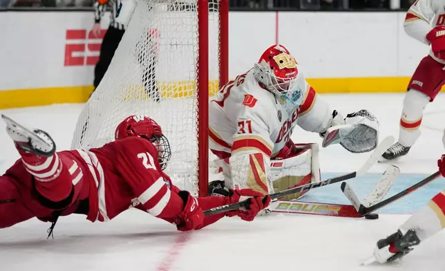 Wisconsin forward Ryan Botterill (21) dives to attempt a shot on Denver goaltender Johnny Hicks (31) in the second period of the championship game at the NCAA Frozen Four men's college hockey tournament Saturday, April 11, 2026, in Las Vegas. (AP Photo/John Locher)