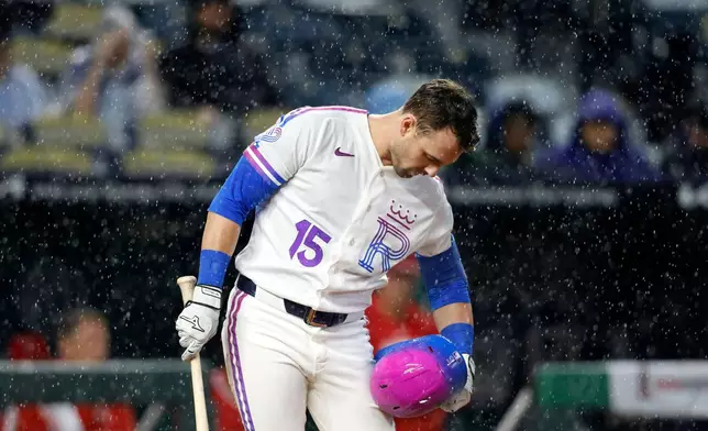 Kansas City Royals batter Lane Thomas wipes off his helmet during a downpour during in the seventh inning of a baseball game against the Los Angeles Angels in Kansas City, Mo., Sunday, April 26, 2026. (AP Photo/Colin E. Braley)