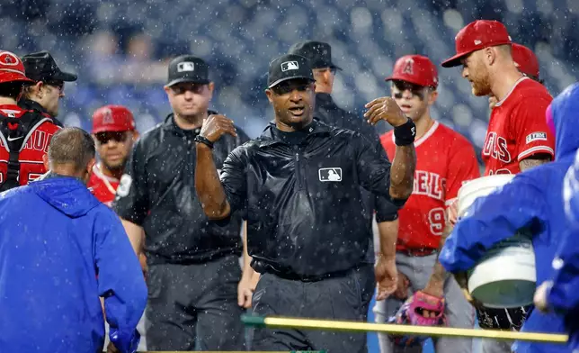 Umpire Alan Porter, center, calls for a rain delay as Los Angeles Angels players and members of the Kansas City Royals grounds crew stand on the pitchers mound during the seventh inning of a baseball game in Kansas City, Mo., Sunday, April 26, 2026. (AP Photo/Colin E. Braley)