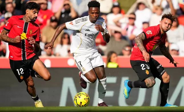 Real Madrid's Vinicius Junior in action betweem Mallorca's Samu Costa, left, and Pablo Maffeo during a La Liga soccer match between Mallorca and Real Madrid in Palma de Mallorca, Spain, Saturday, April 4, 2026. (AP Photo/Jose Breton)