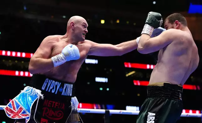 Boxer Tyson Fury, left, punches Arslanbek Makhmudov during a heavyweight bout at Tottenham Hotspur Stadium in London, Saturday, April 11, 2026. (Bradley Collyer/PA via AP)
