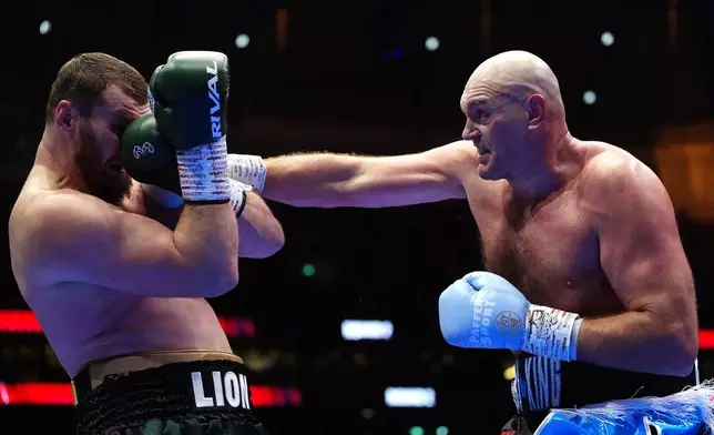 Boxer Tyson Fury, right, punches Arslanbek Makhmudov during a heavyweight bout at Tottenham Hotspur Stadium in London, Saturday, April 11, 2026. (Bradley Collyer/PA via AP)