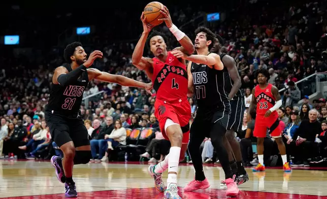 Toronto Raptors forward Scottie Barnes (4) drives past Brooklyn Nets forward Chaney Johnson (31) and teammate Michael Porter Jr. (17) during first half NBA basketball action in Toronto, Sunday, April 12, 2026. (Frank Gunn/The Canadian Press via AP)