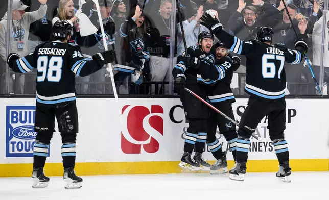 Utah Mammoth right wing Clayton Keller, center left, reacts to scoring a goal with teammates Utah Mammoth defenseman MacKenzie Weegar, center right, Utah Mammoth left wing Lawson Crouse, right, and Utah Mammoth defenseman Mikhail Sergachev, left, during the third period of Game 4 of a first-round NHL hockey Stanley Cup playoff series, Monday, April 27, 2026, in Salt Lake City. (AP Photo/Tyler Tate)