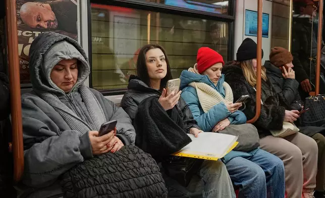 FILE - Passengers look at their smartphones in the subway in Moscow, Feb. 11, 2026. (AP Photo/Alexander Zemlianichenko, File)