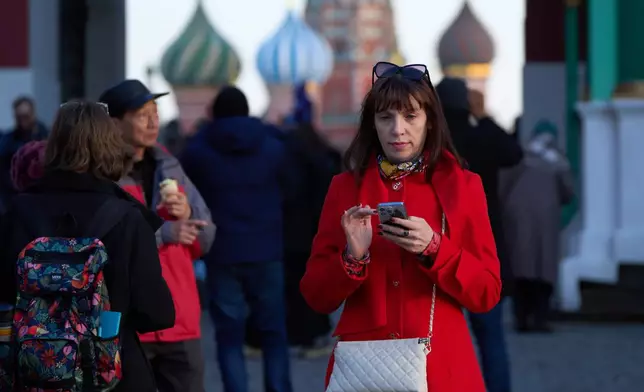 FILE - A woman holding her smartphone leaves Red Square in Moscow, March 11, 2026. (AP Photo/Alexander Zemlianichenko, File)