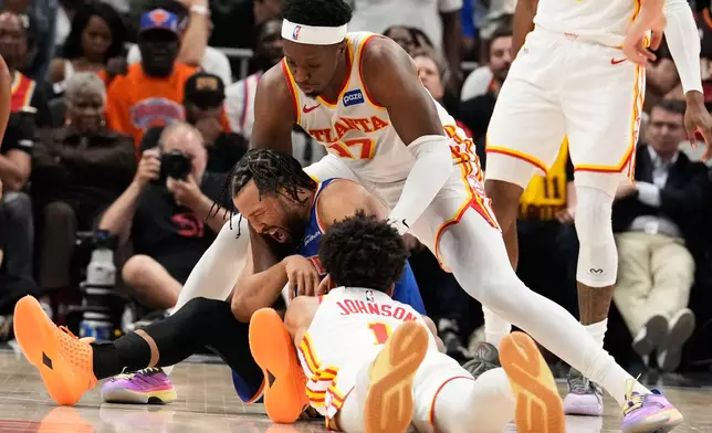 New York Knicks guard Jalen Brunson (11) fights for the ball against Atlanta Hawks' Jalen Johnson (1) and Onyeka Okongwu (17) during the first half of Game 4 in a first-round NBA playoffs basketball series Saturday, April 25, 2026, in Atlanta. (AP Photo/Brynn Anderson)