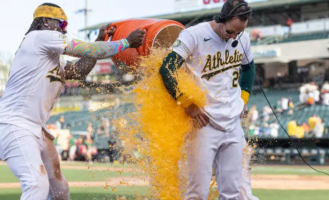 Athletics' Lawrence Butler, left, and Max Muncy dump Gatorade on Brent Rooker, right, after he hit a walk-off three-run home run during the tenth inning of a baseball game against the Houston Astros Sunday, April 5, 2026, in West Sacramento, Calif. (AP Photo/Sara Nevis)