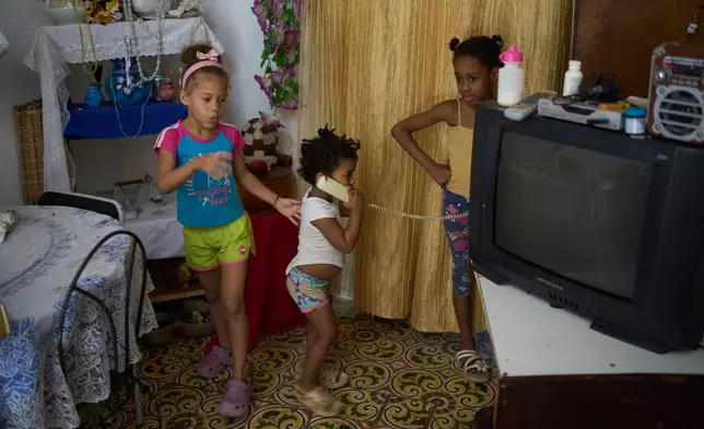 Edianet, left, and her sister Seinet, center, play with a friend at their home in Havana, Cuba, Wednesday, March 25, 2026. (AP Photo/Ramon Espinosa)