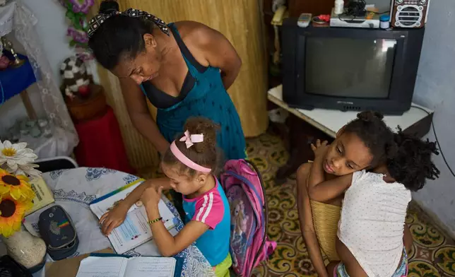 Yuneisy Riviaux helps her daughter Edianet with her homework at home in Havana, Cuba, Wednesday, March 25, 2026. (AP Photo/Ramon Espinosa)