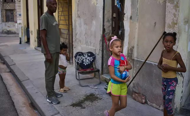 Cristobal Estrada, left, sends his daughter Edianet, center, with a bag of rice to their home in Havana, Cuba, Wednesday, March 25, 2026. (AP Photo/Ramon Espinosa)