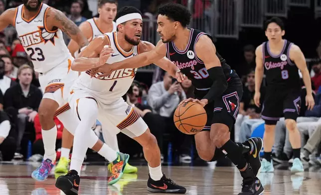 Chicago Bulls guard Tre Jones, right, drives against Phoenix Suns guard Devin Booker during the first half of an NBA basketball game in Chicago, Sunday, April 5, 2026. (AP Photo/Nam Y. Huh)