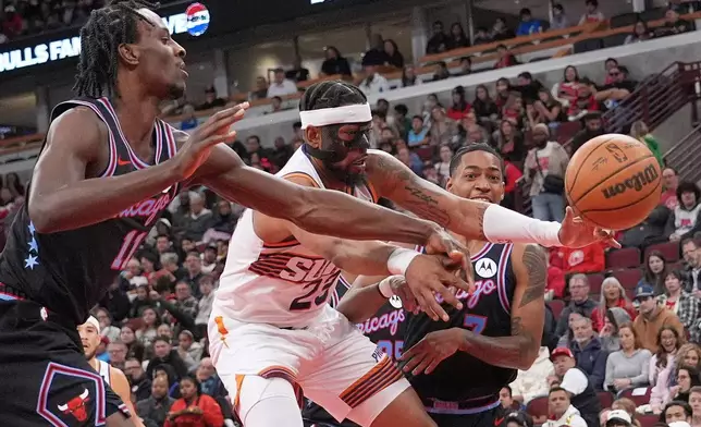 Phoenix Suns guard Jordan Goodwin, center, battles for a rebound against Chicago Bulls forward Leonard Miller, left, and guard Rob Dillingham during the first half of an NBA basketball game in Chicago, Sunday, April 5, 2026. (AP Photo/Nam Y. Huh)