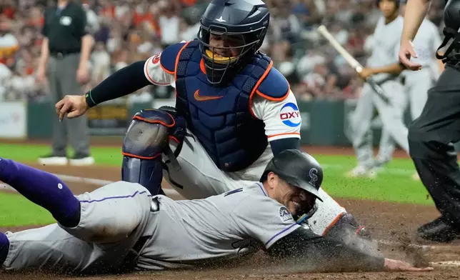 Colorado Rockies' Tyler Freeman, bottom, is tagged out at home plate by Houston Astros catcher Yainer Diaz (21) during the fifth inning of a baseball game Thursday, April 16, 2026, in Houston. (AP Photo/David J. Phillip)