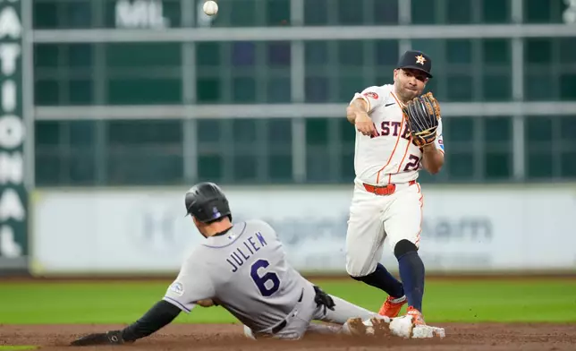 Houston Astros second baseman Jose Altuve (27) turns a double play as Colorado Rockies' Edouard Julien (6) slides into second base during the third inning of a baseball game Thursday, April 16, 2026, in Houston. (AP Photo/David J. Phillip)