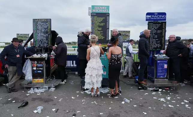 Racegoers stand at a betting booth on Ladies Day, the second day of the Grand National Horse Racing festival, at Aintree racecourse, near Liverpool, England, Friday, April 10, 2026. (AP Photo/Jon Super)