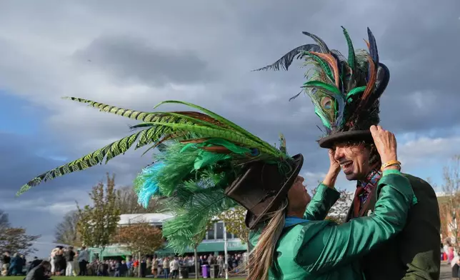 Racegoers adjust their hats on Ladies Day, the second day of the Grand National Horse Racing festival, at Aintree racecourse, near Liverpool, England, Friday, April 10, 2026. (AP Photo/Jon Super)