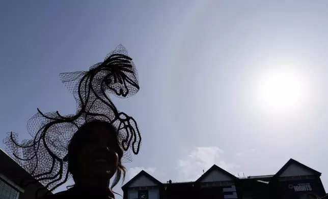 A racegoer is silhouetted as she attends Ladies Day, the second day of the Grand National Horse Racing festival, at Aintree racecourse, near Liverpool, England, Friday, April 10, 2026. (AP Photo/Jon Super)