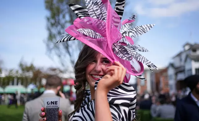 A racegoer poses as she attends Ladies Day, the second day of the Grand National Horse Racing festival, at Aintree racecourse, near Liverpool, England, Friday, April 10, 2026. (AP Photo/Jon Super)
