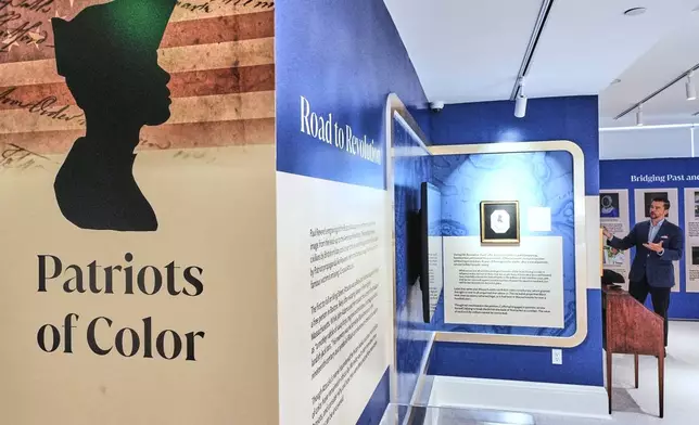 Ryan J. Woods, President &amp; Chief Executive Officer of the American Ancestors museum, far right, gives a tour of the "Patriots of Color" exhibition at the museum, Wednesday, April 15, 2026, in Boston. (AP Photo/Charles Krupa)