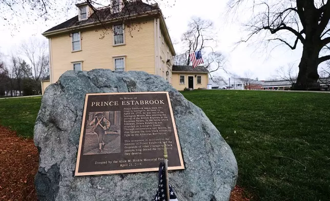 A memorial for enslaved Minuteman Prince Estabrook, which features an image of Revolutionary War re-enactor and Korean War veteran Charles Price, is displayed near the village green, Monday, April 13, 2026, in Lexington, Mass. (AP Photo/Charles Krupa)