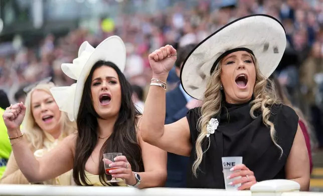 Reacgoers react as they watch the Jet2 Liverpool Hurdle during the Grand National horse race meeting at Aintree racecourse in Liverpool, Saturday, April 11, 2026. (AP Photo/Jon Super)