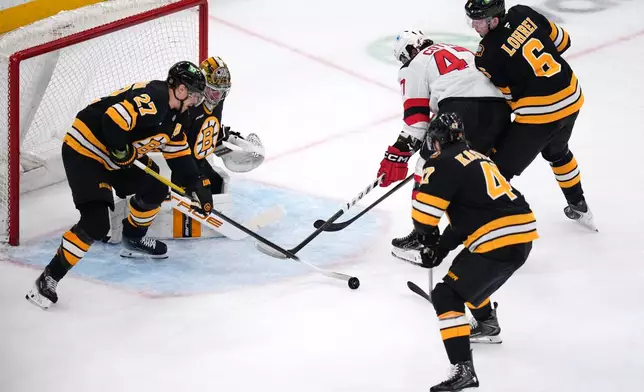 New Jersey Devils left wing Paul Cotter (47) is surrounded by Boston Bruins players while trying to shoot during the first period of a hockey game, Tuesday, April 14, 2026, in Boston. (AP Photo/Charles Krupa)