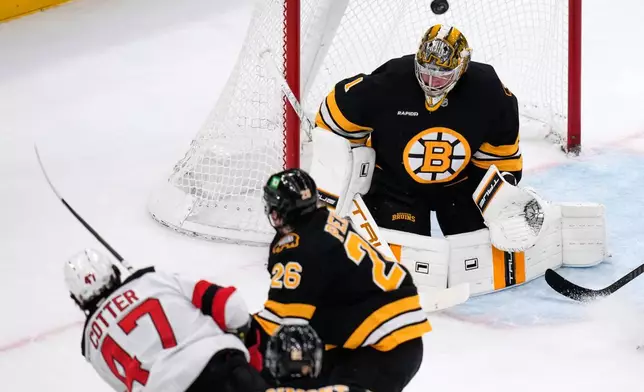 Boston Bruins goaltender Jeremy Swayman (1) makes a save on a shot by New Jersey Devils left wing Paul Cotter (47) during the first period of a hockey game, Tuesday, April 14, 2026, in Boston. (AP Photo/Charles Krupa)